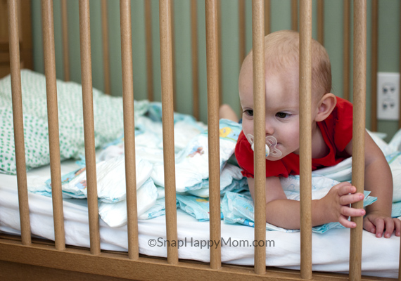 toddler girl playing in crib with diapers