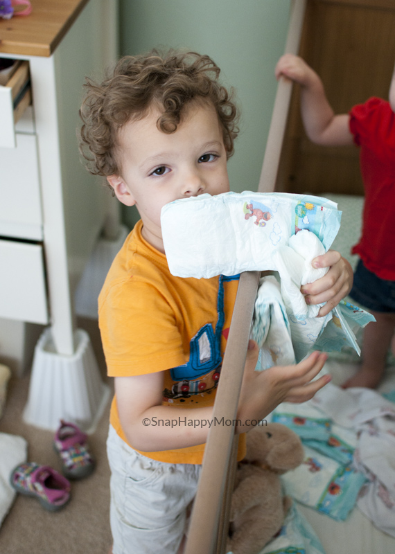 boy putting diapers in crib